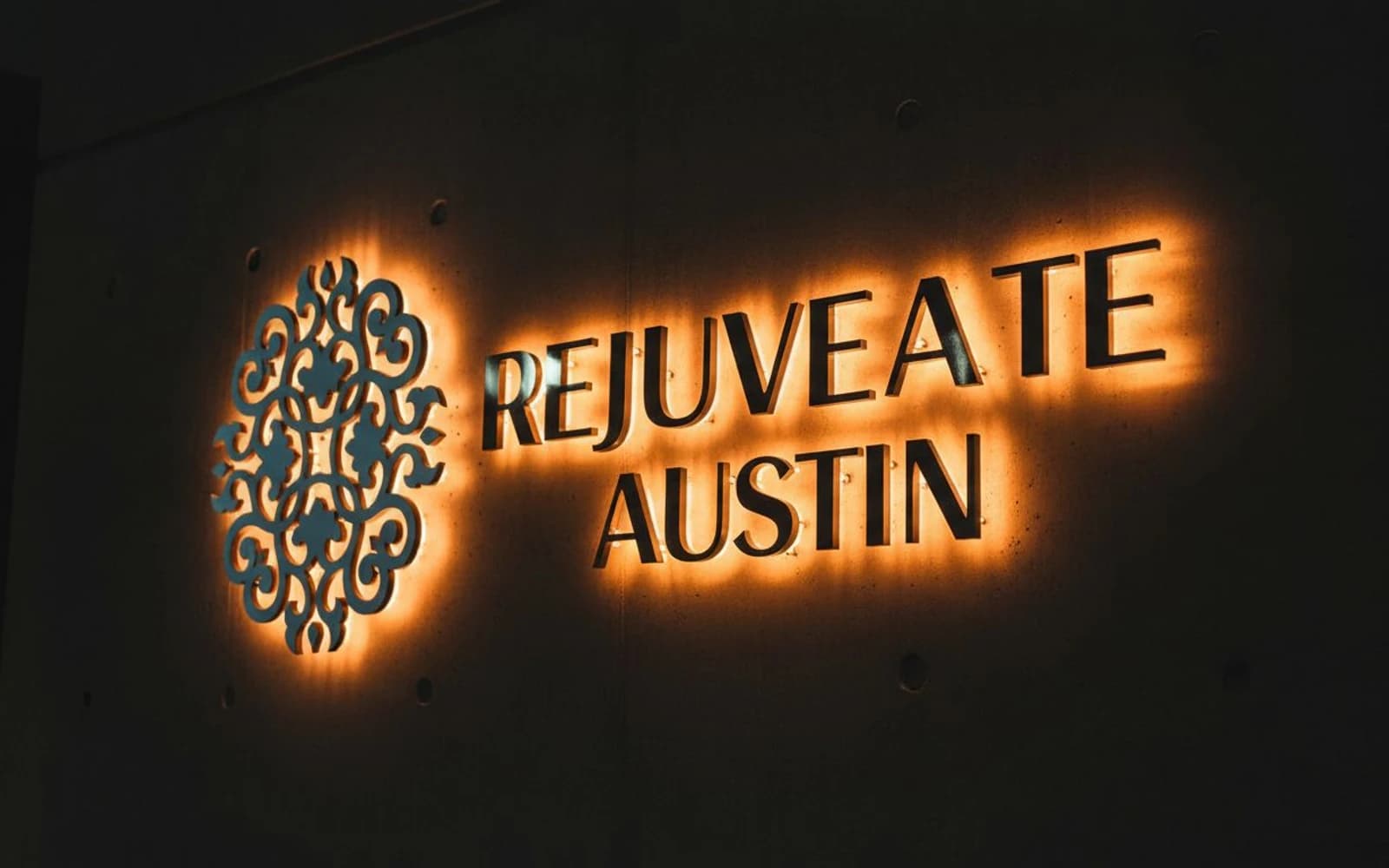 Halo-lit ornamental logo and wordmark on dark concrete wall