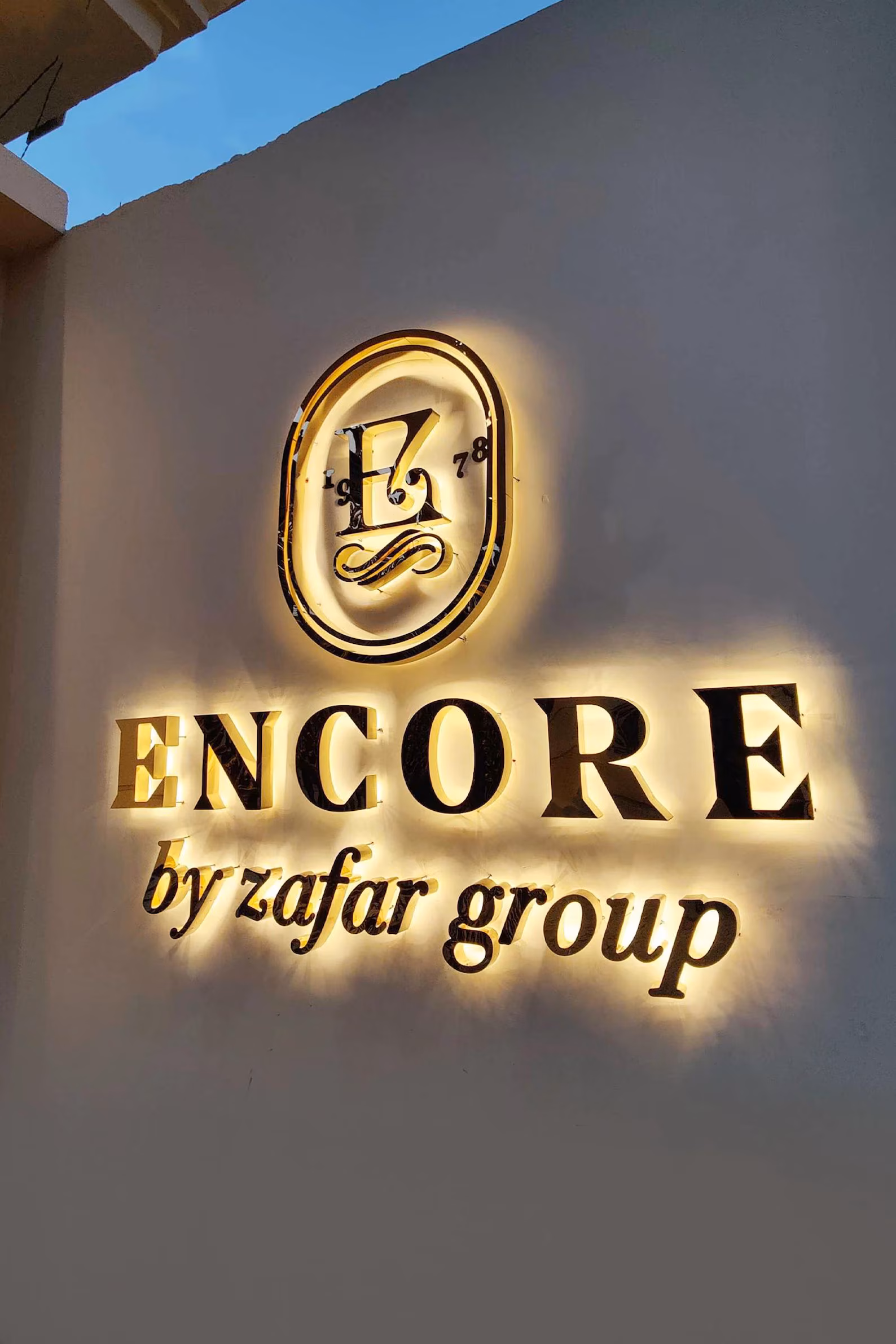 Warm halo-lit metal letters on outdoor restaurant wall at dusk