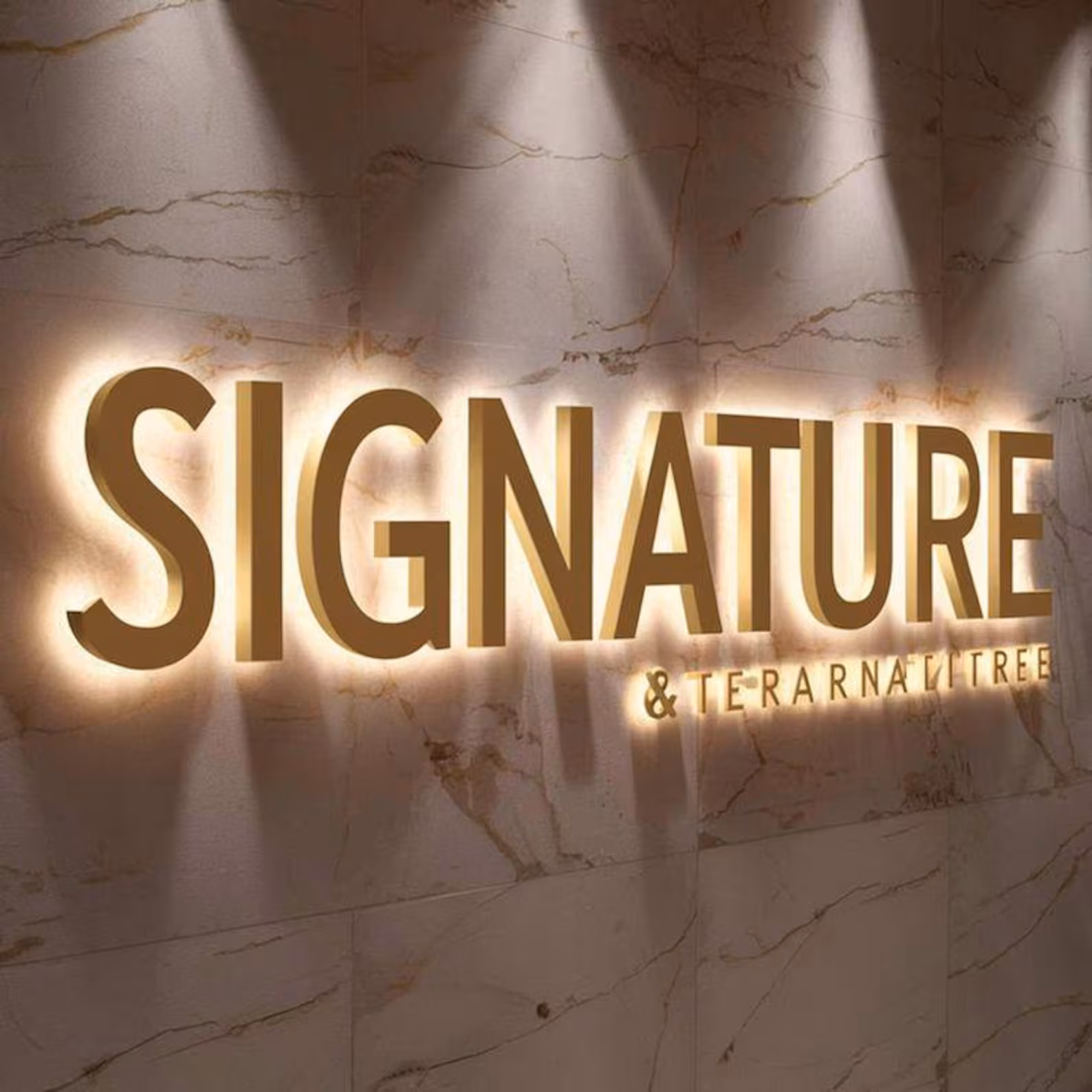Gold halo-lit signature lettering on veined marble lobby wall